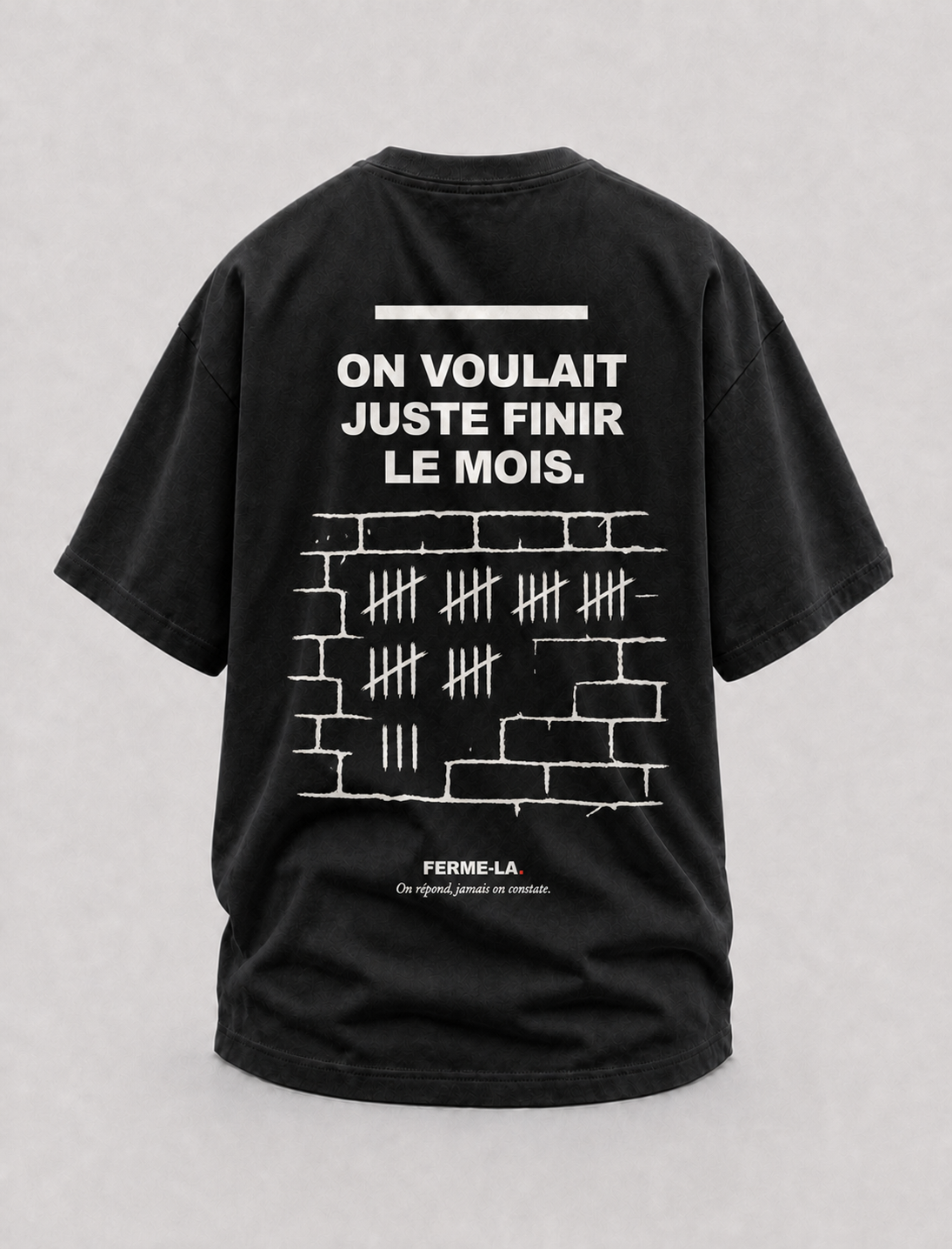 T-shirt noir Ferme-la., dos : ON VOULAIT JUSTE FINIR LE MOIS., des bâtons comptés à la craie sur un mur de briques.