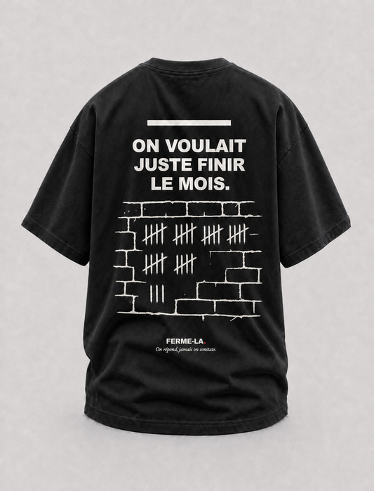 T-shirt noir Ferme-la., dos : ON VOULAIT JUSTE FINIR LE MOIS., des bâtons comptés à la craie sur un mur de briques.